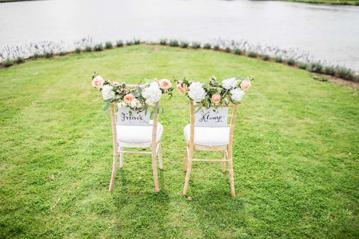 Bruidstoelen met bloemen aan het water